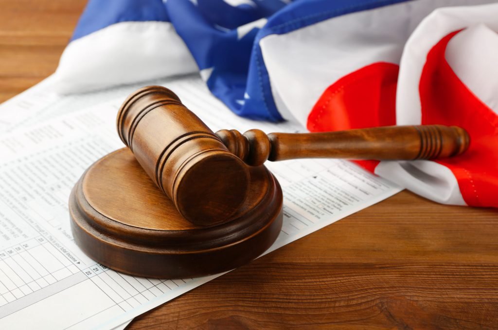 Judge's gavel with individual tax return form and American flag on wooden table